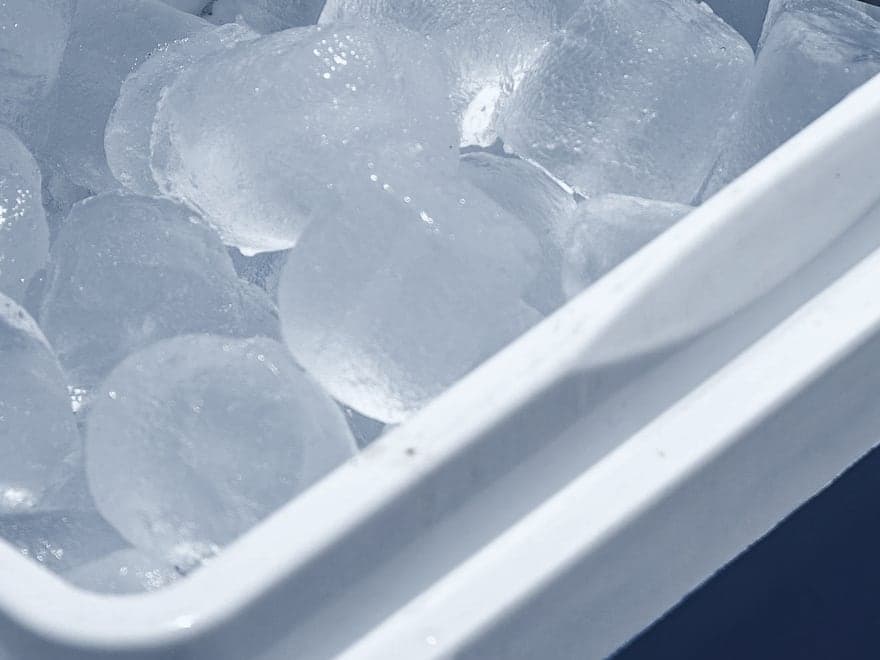 A cooler box packed to the rim with ice cubes.